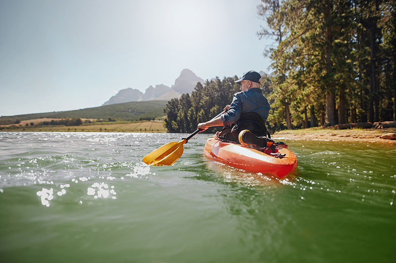 Old man paddling a kayak on a summer day