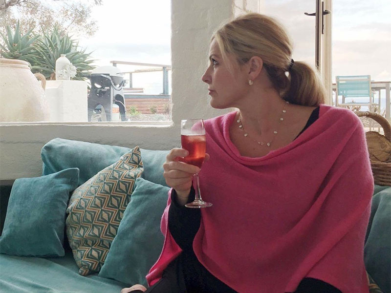 Kristen Meckam sitting on a couch holding a glass of wine
