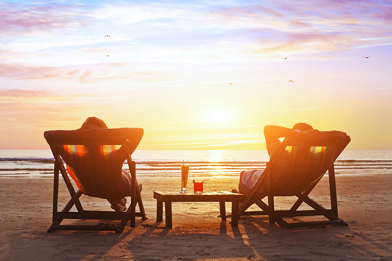 couple relaxing on beach in beach chairs 