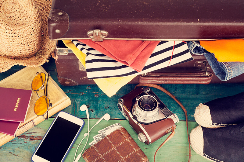 overflowing womens suitcase with iPhone and camera