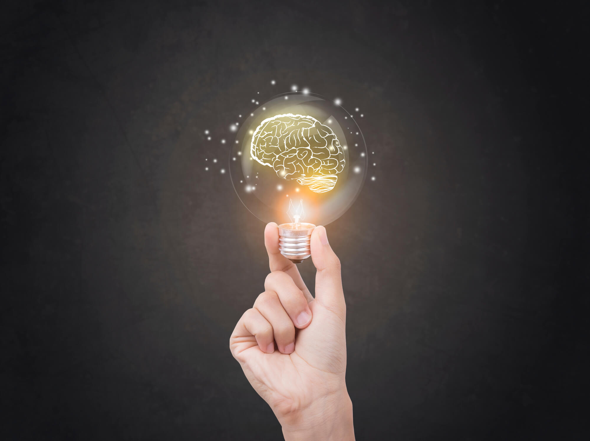 Hand holding a light bulb with a brain inside it