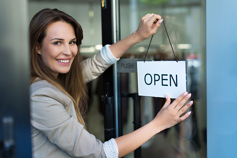 Woman hanging an open sign on a small business