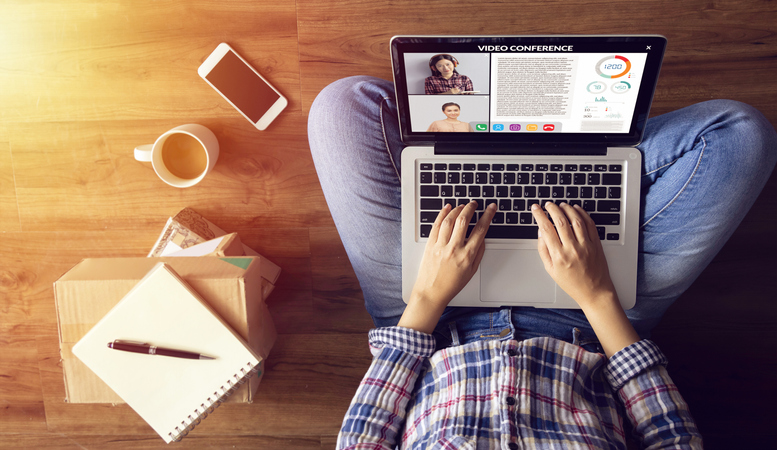 A woman working remotely with her laptop on her lap