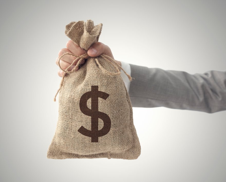 A person holds out a bag of money