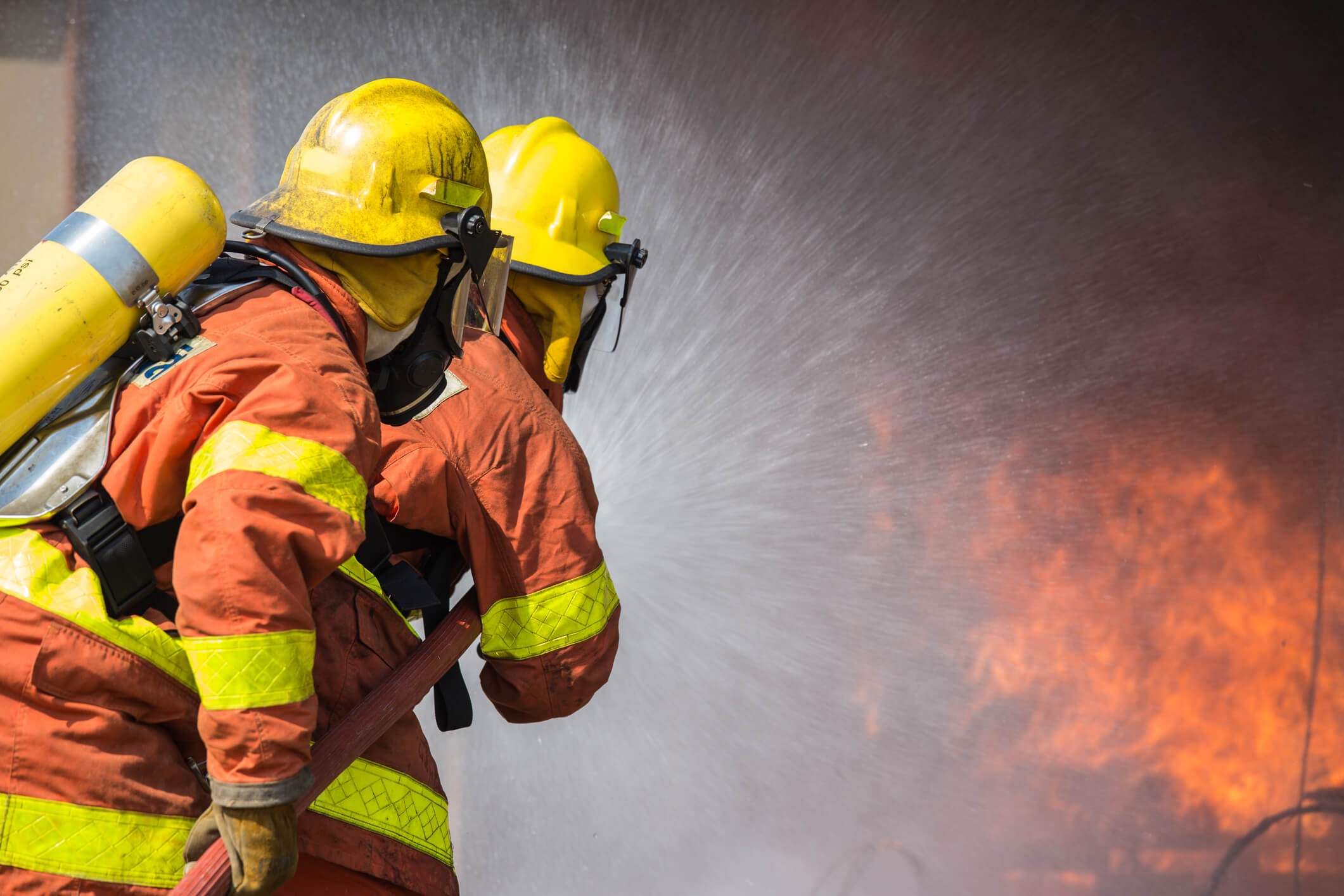 Firefighters training a hose on a fire