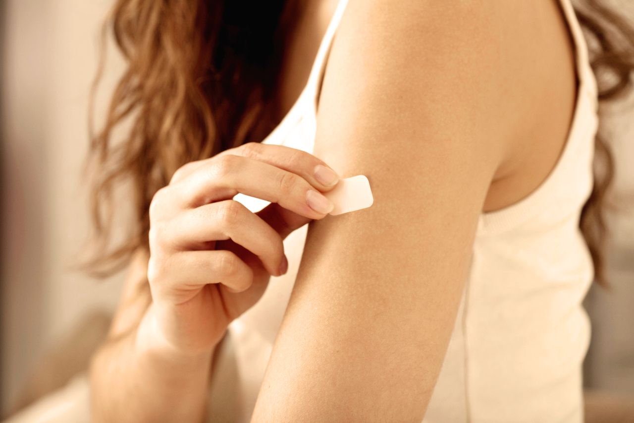 Woman places hormone therapy patch for menopause on arm