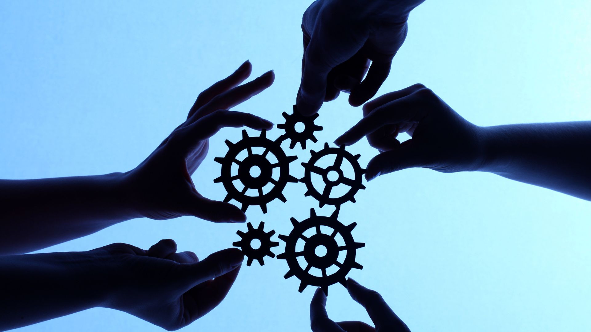 Silhouette of hands holding cogs and gears