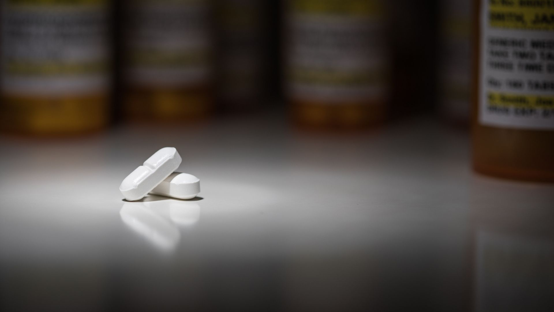Hydrocodone pills and prescription bottles under spot light