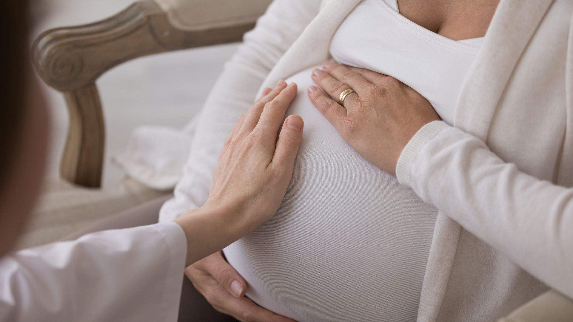 Closeup caring doula consults expectant mother touch her belly closeup