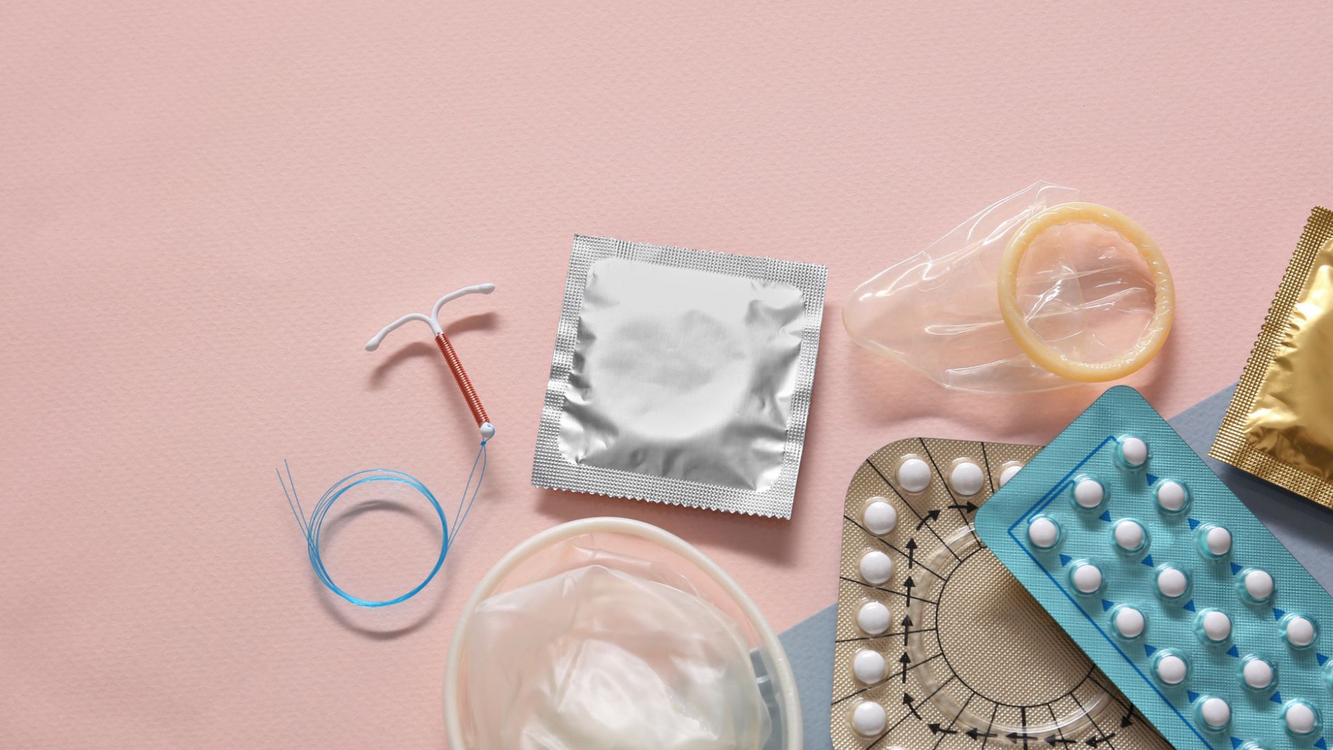 Contraceptive pills condoms and intrauterine device on beige background