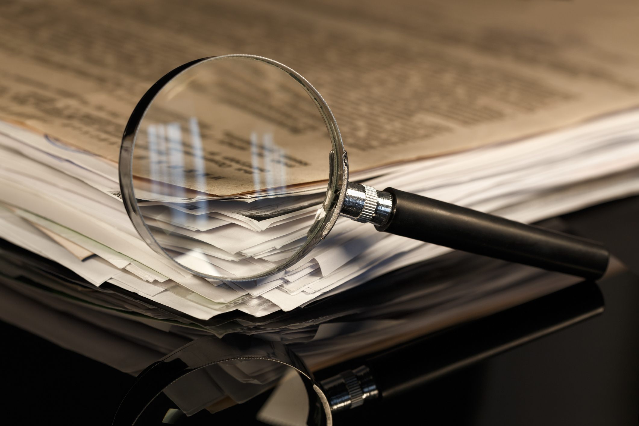 Magnifying glass with stack of papers