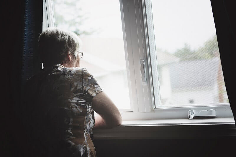 Isolated senior citizen looking out window