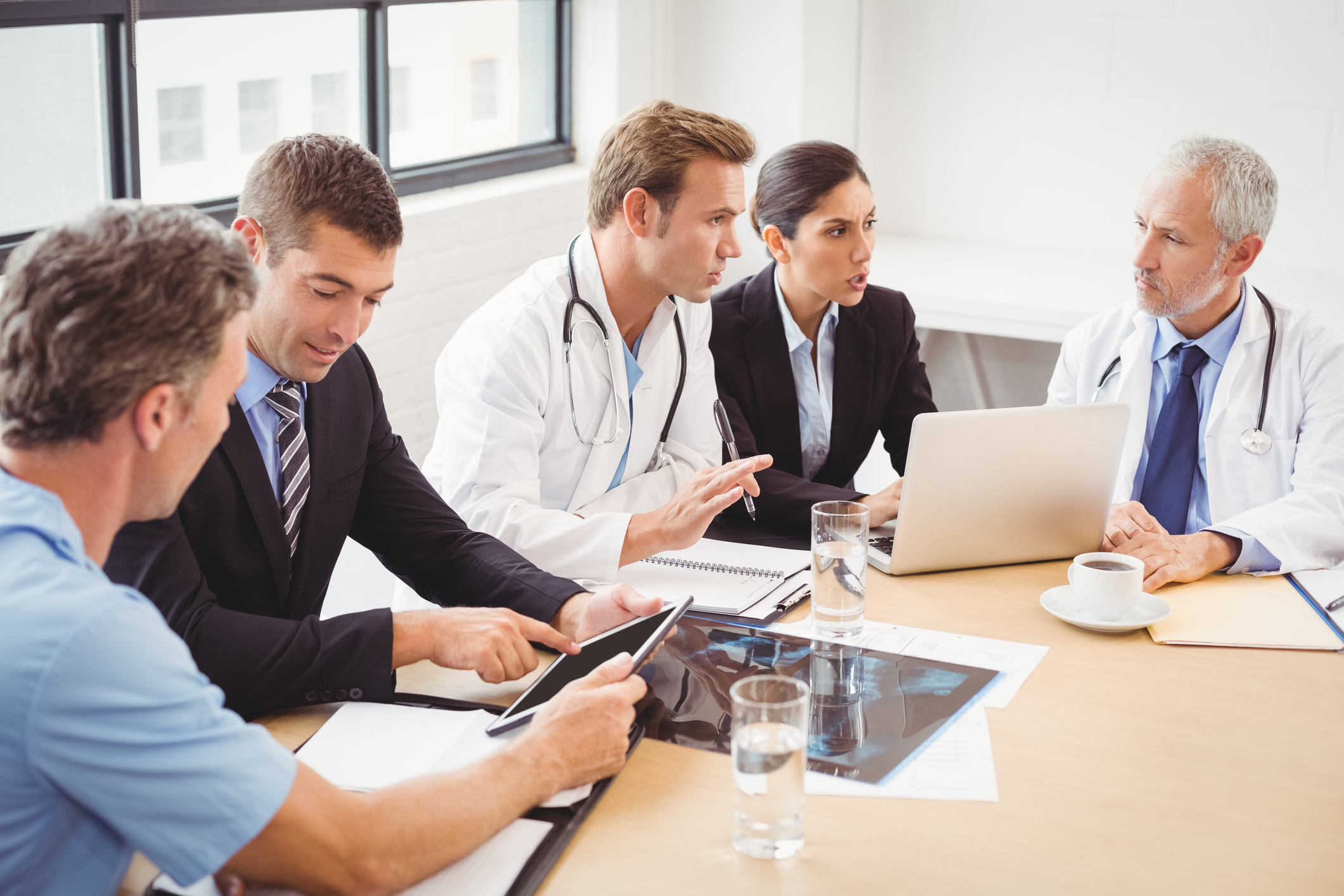 Doctors and businesspeople discussing in groups with computers