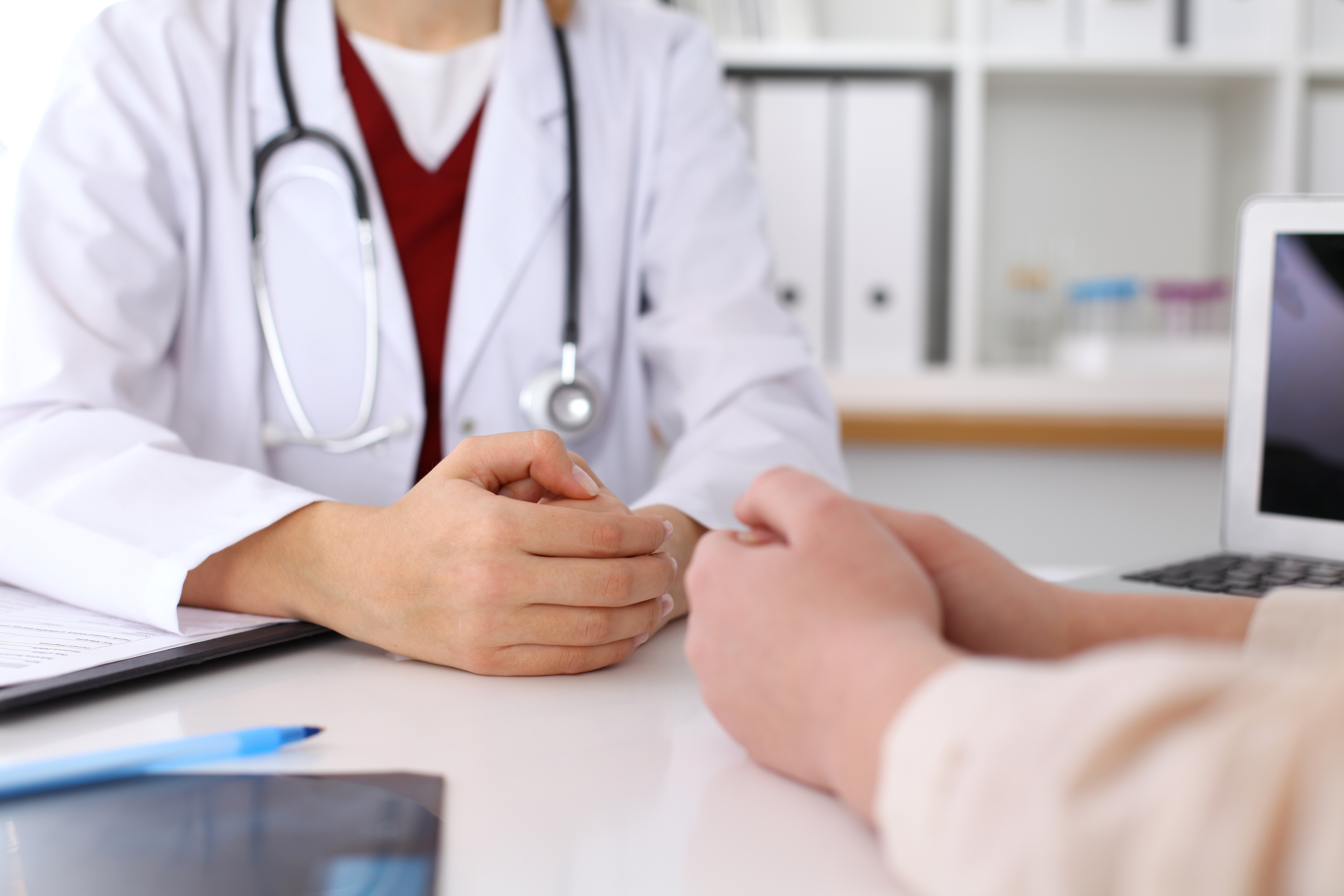 Photo of doctor and patient hands while discussing medical records after health examination