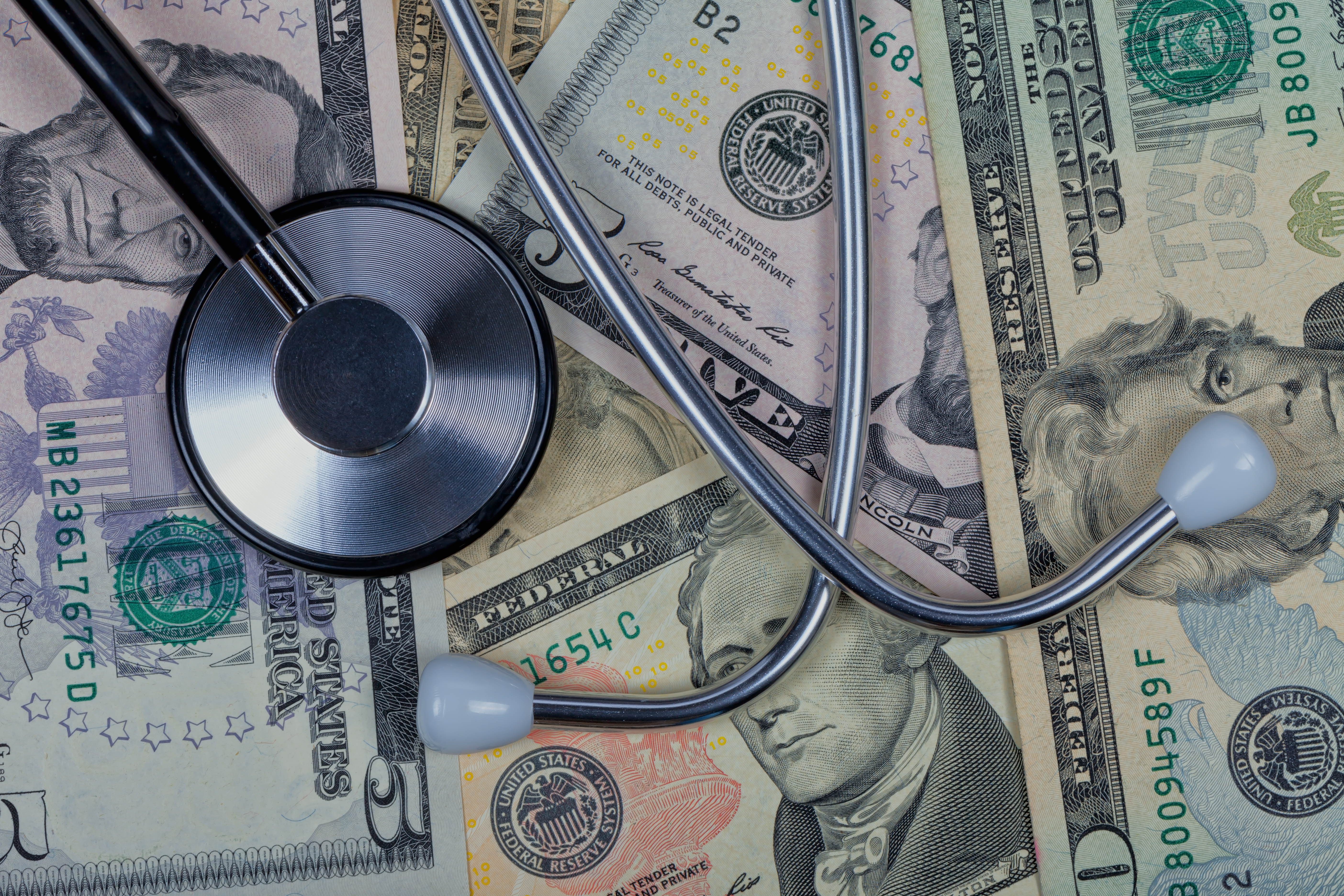 Stethoscope on top of five ten and twenty dollar bills