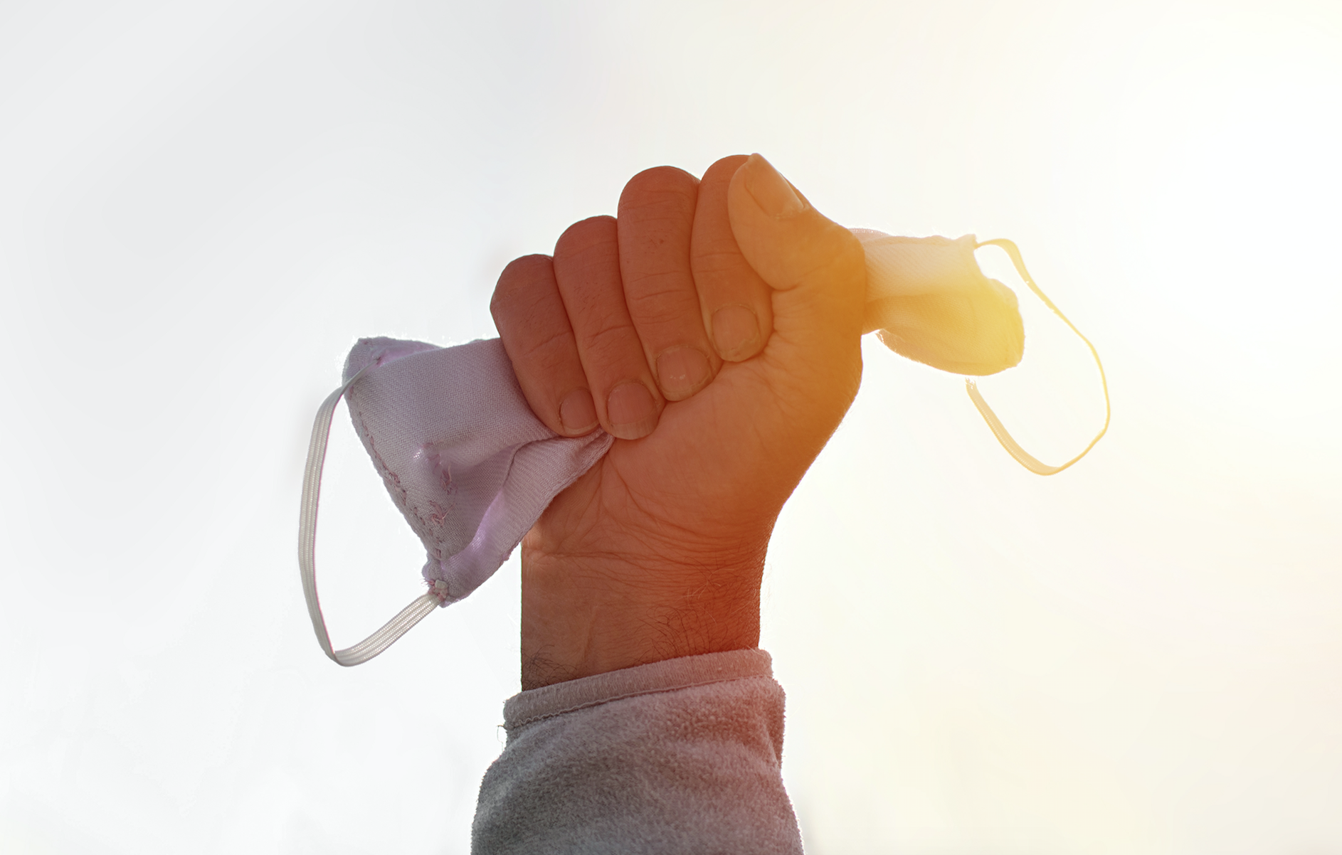 A hand held up clenching a face mask