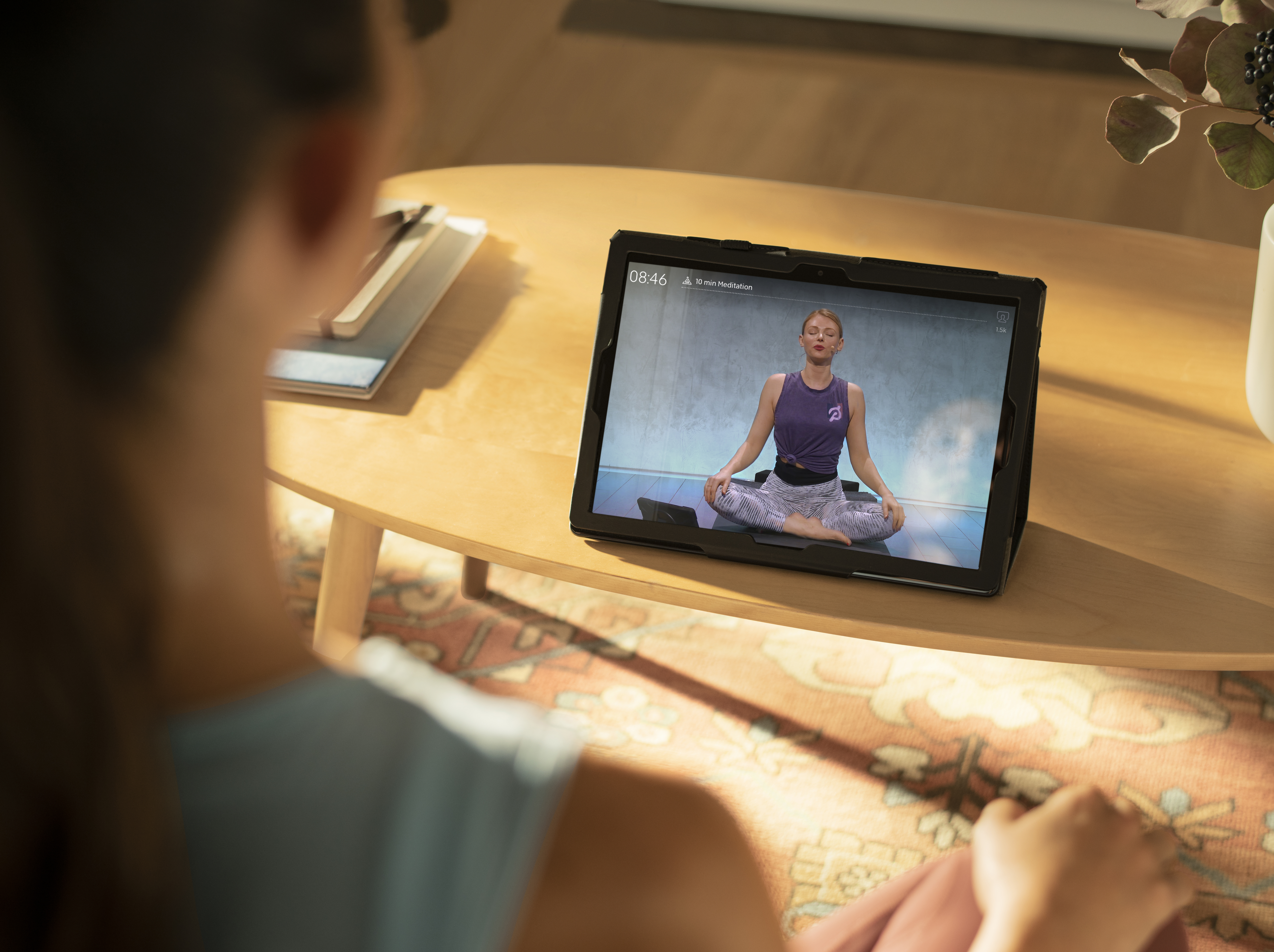 woman doing meditation exercises with laptop screen showing Peloton app