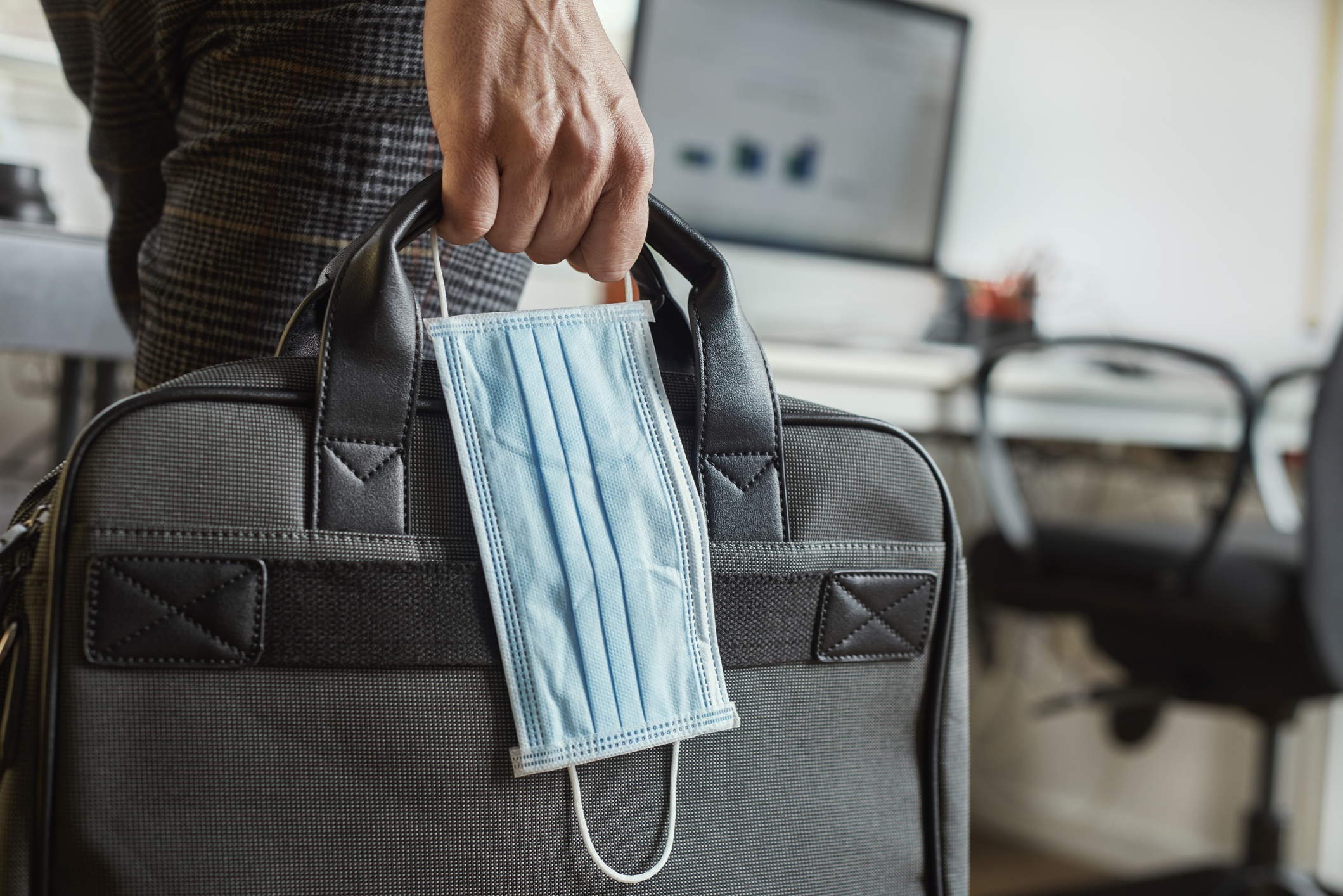 Person holds mask and briefcase