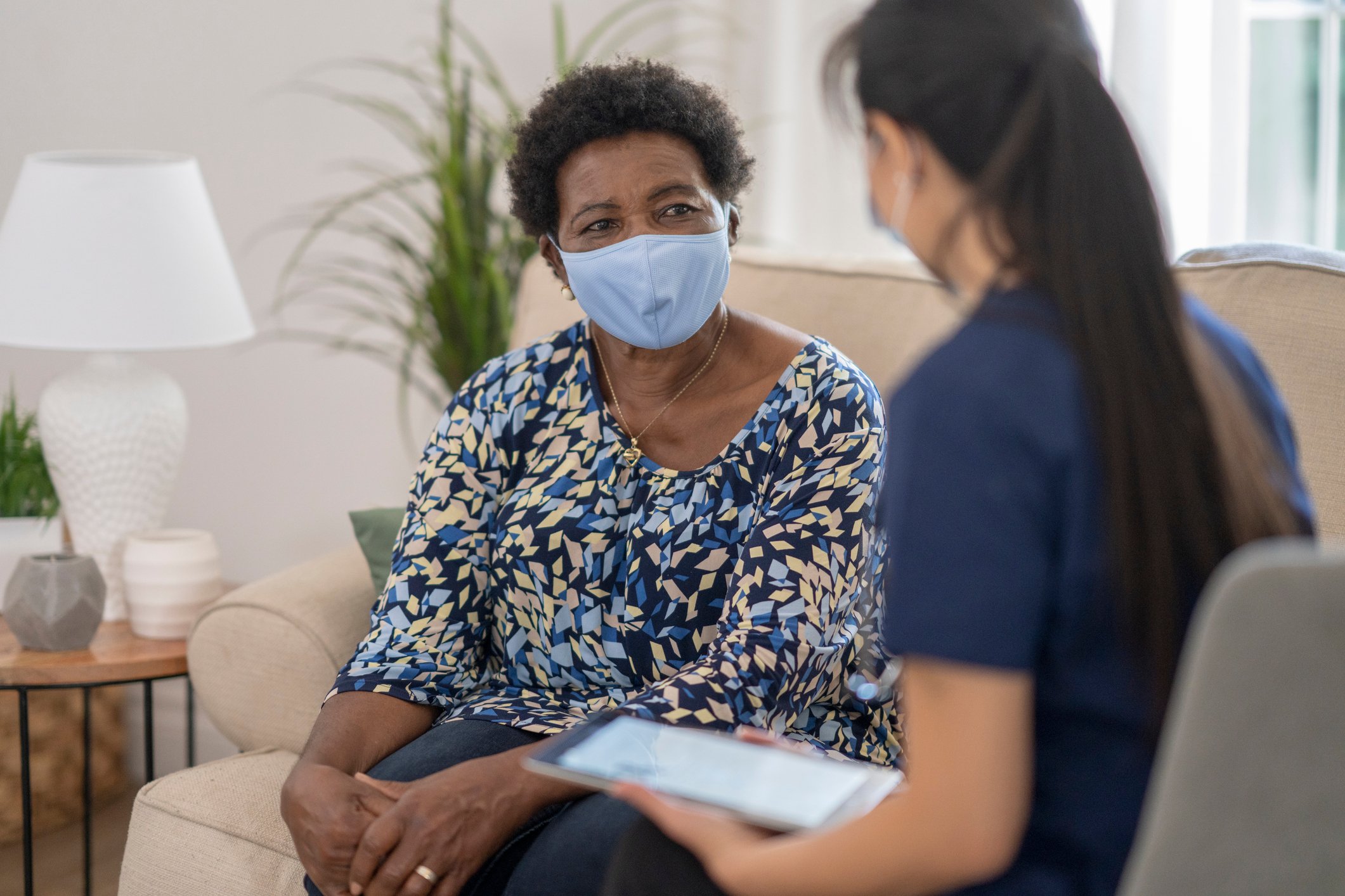 A provider speaking with a patient at home with a tablet