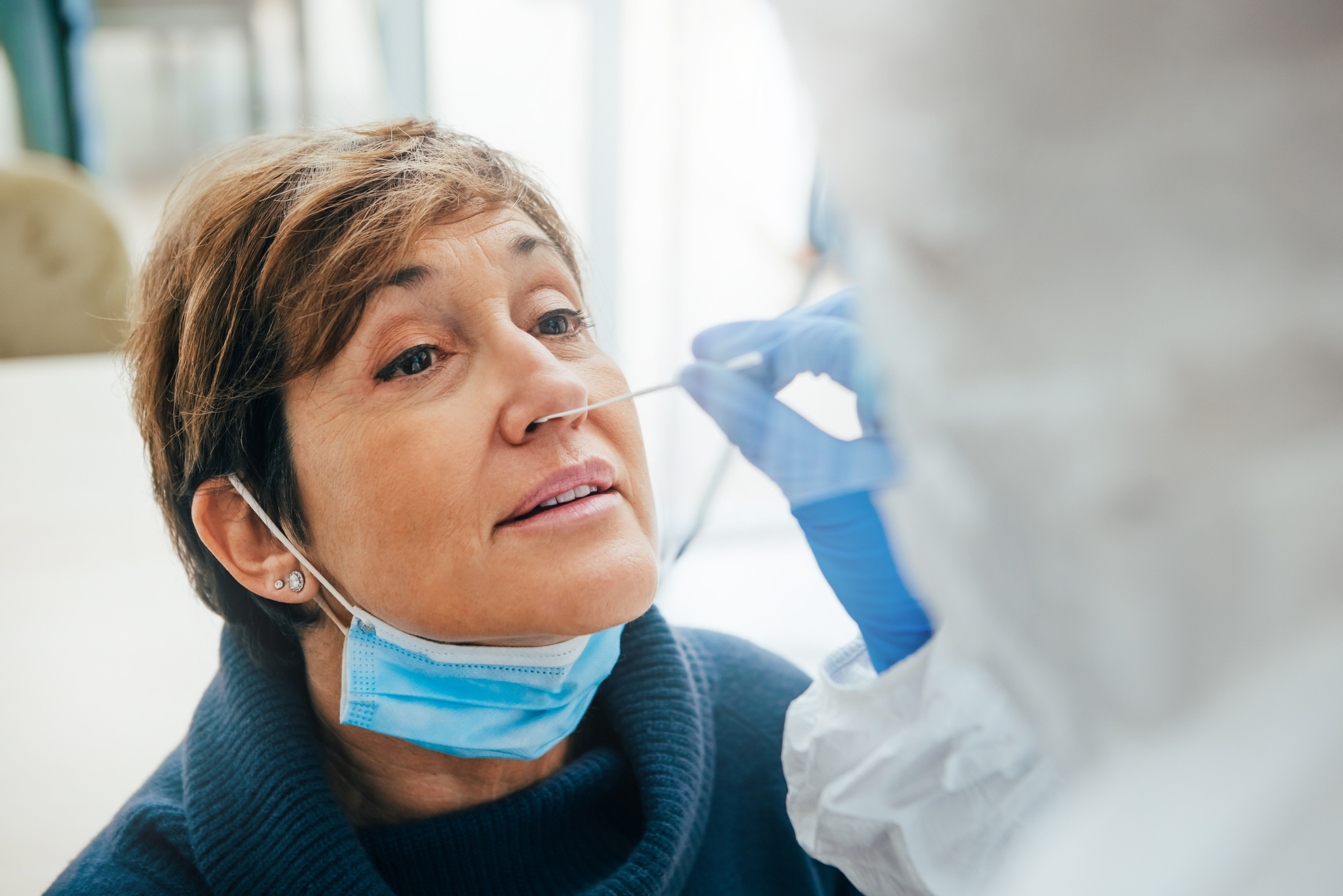 lose up of the face of senior female patient being tested for Covid-19 with a nasal swab by a health professional protected 
