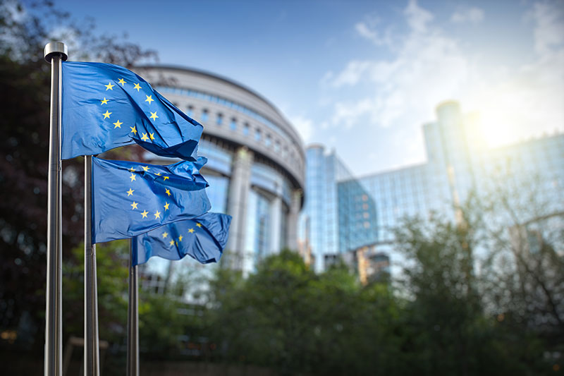 European Union flags waving in front of the EU Parliament building in Brussels