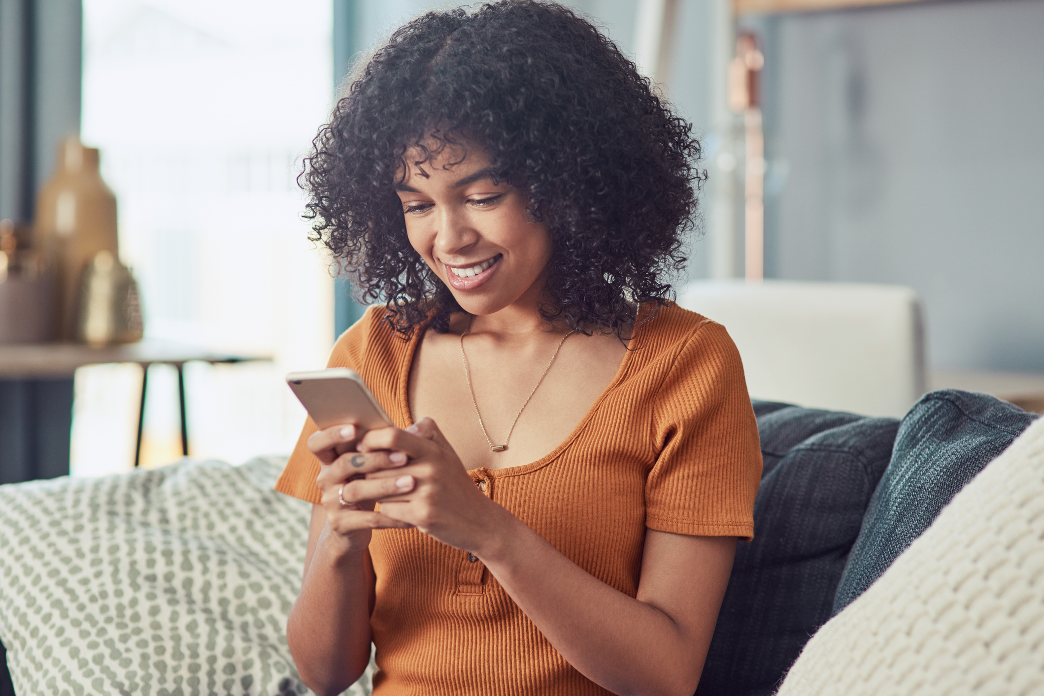 a young woman using a smartphone on the sofa at home